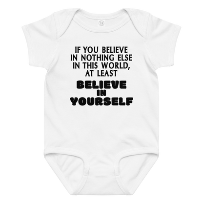 "If you believe in nothing else in this world, at least believe in yourself" printed on a white baby jersey bodysuit laying on a flat surface amongst other clothes