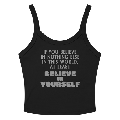 "If you believe in nothing else in this world, at least believe in yourself" printed on a solid black blend women's micro-rib tanktop laying on a flat surface amongst sunglasses and shorts