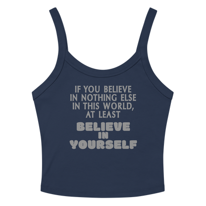 "If you believe in nothing else in this world, at least believe in yourself" printed on a solid navy blend women's micro-rib tanktop laying on a flat surface amongst sunglasses and shorts