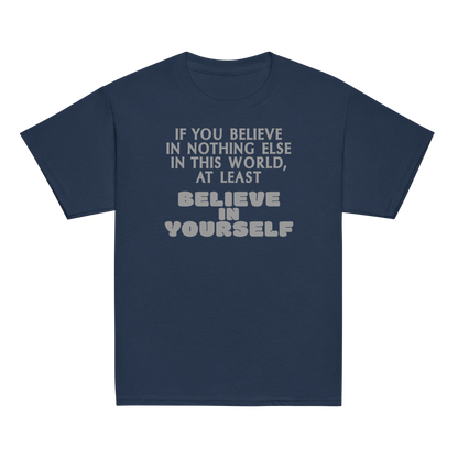 "If you believe in nothing else in this world, at least believe in yourself" printed on a navy youth classic tee laying on a flat surface