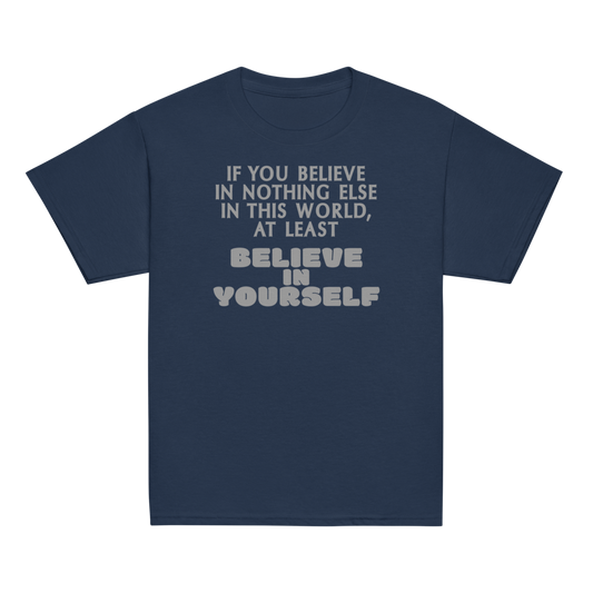 "If you believe in nothing else in this world, at least believe in yourself" printed on a navy youth classic tee laying on a flat surface