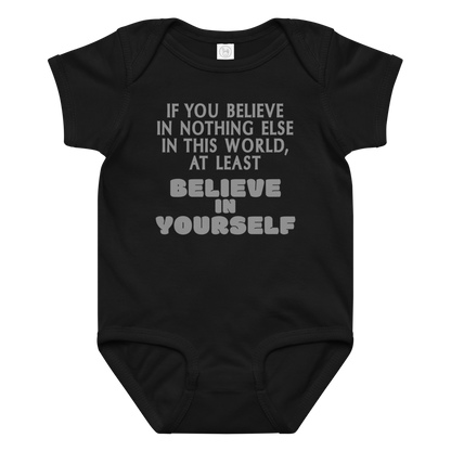 "If you believe in nothing else in this world, at least believe in yourself" printed on a black baby jersey bodysuit laying on a flat surface amongst other clothes