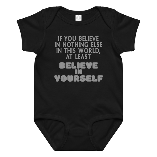 "If you believe in nothing else in this world, at least believe in yourself" printed on a black baby jersey bodysuit laying on a flat surface amongst other clothes