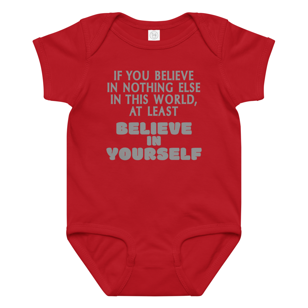 "If you believe in nothing else in this world, at least believe in yourself" printed on a red baby jersey bodysuit laying on a flat surface amongst other clothes
