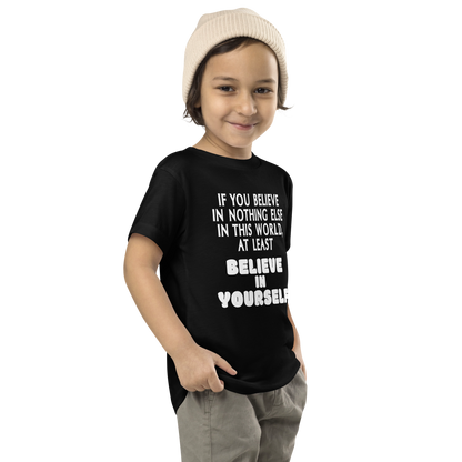 "If you believe in nothing else in this world, at least believe in yourself" printed on a black toddler short sleeve tee worn by a male who is also wearing a knit cap
