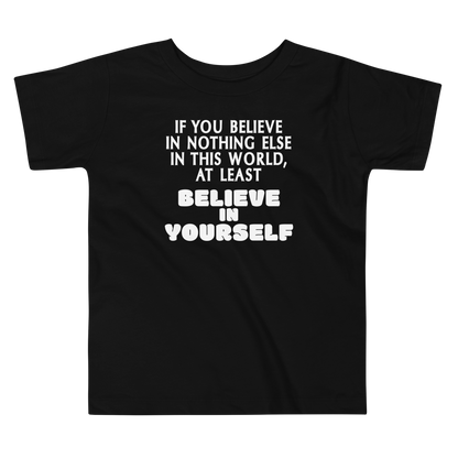 "If you believe in nothing else in this world, at least believe in yourself" printed on a black toddler short sleeve tee laying on a flat surface