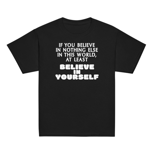 "If you believe in nothing else in this world, at least believe in yourself" printed on a black youth classic tee laying on a flat surface