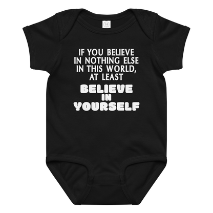 "If you believe in nothing else in this world, at least believe in yourself" printed on a black baby jersey bodysuit laying on a flat surface amongst other clothes