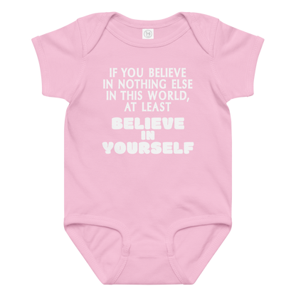 "If you believe in nothing else in this world, at least believe in yourself" printed on a pink baby jersey bodysuit laying on a flat surface amongst other clothes