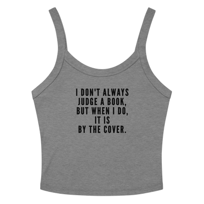 "I Don't always Judge a Book, but when I do, it's by the cover." printed on a athletic heather women's micro-rib tanktop laying on a flat surface amongst sunglasses and shorts
