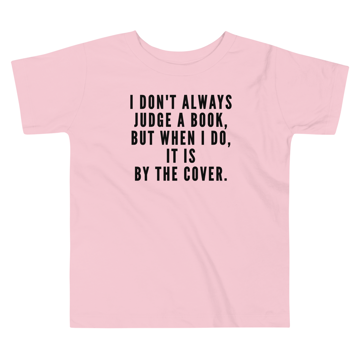 "I Don't always Judge a Book, but when I do, it's by the cover." printed on a pink toddler short sleeve tee laying on a flat surface