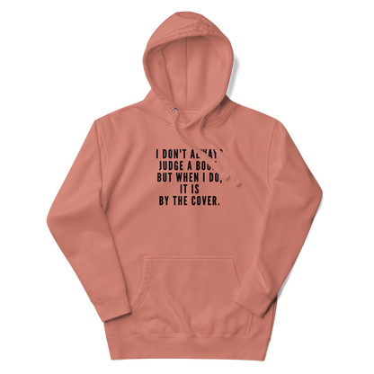 "I Don't always Judge a Book, but when I do, it's by the cover." printed on a dusty rose unisex hoodie laying on a flat surface with the hood up