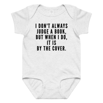 "I Don't always Judge a Book, but when I do, it's by the cover." printed on a ash baby jersey bodysuit laying on a flat surface amongst other clothes