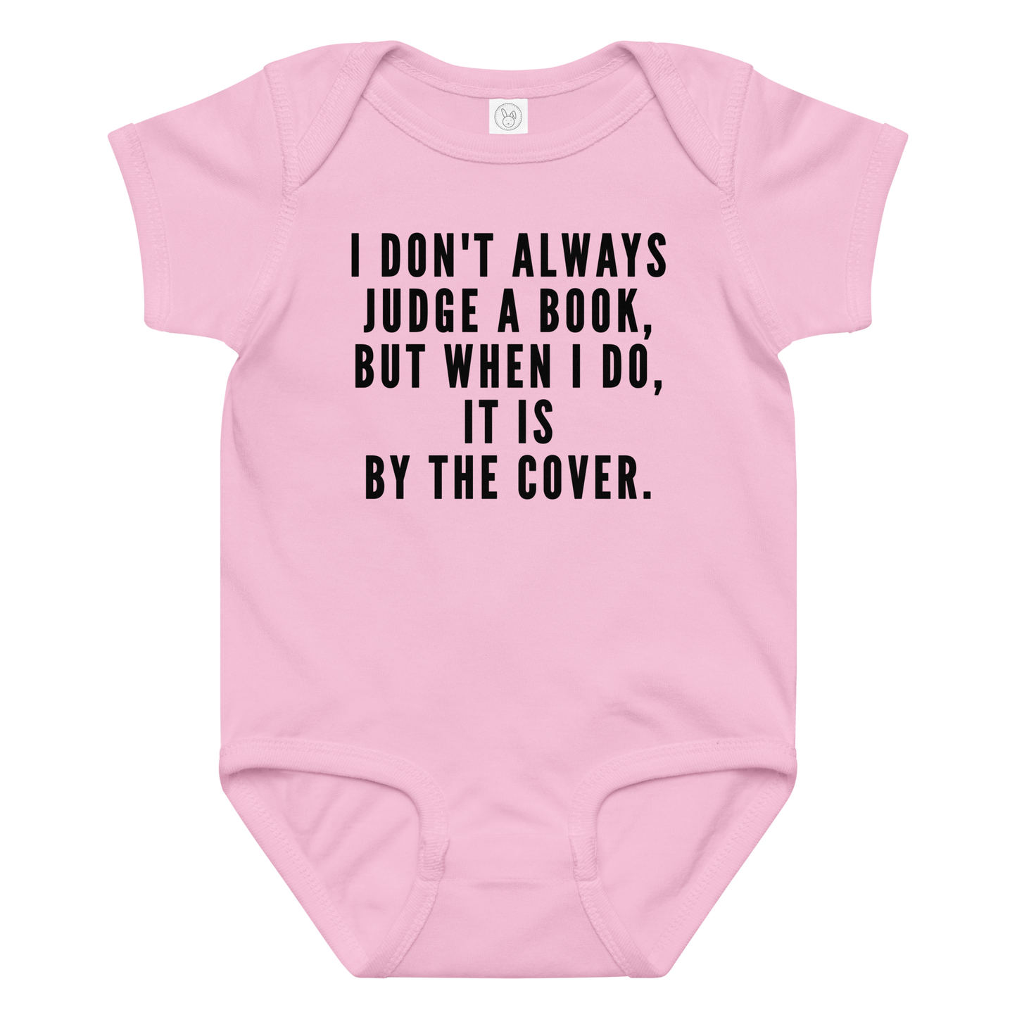 "I Don't always Judge a Book, but when I do, it's by the cover." printed on a pink baby jersey bodysuit laying on a flat surface amongst other clothes