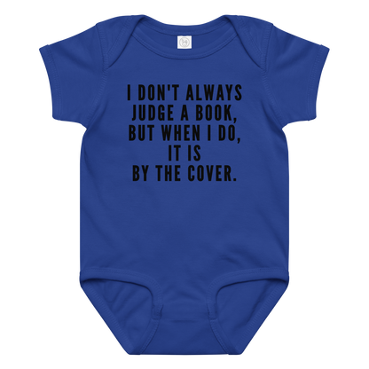 "I Don't always Judge a Book, but when I do, it's by the cover." printed on a royal baby jersey bodysuit laying on a flat surface amongst other clothes