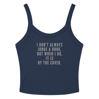 "I Don't always Judge a Book, but when I do, it's by the cover." printed on a solid navy blend women's micro-rib tanktop laying on a flat surface amongst sunglasses and shorts