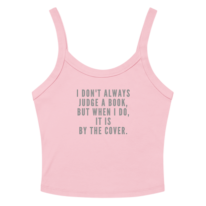 "I Don't always Judge a Book, but when I do, it's by the cover." printed on a solid pink blend women's micro-rib tanktop laying on a flat surface amongst sunglasses and shorts