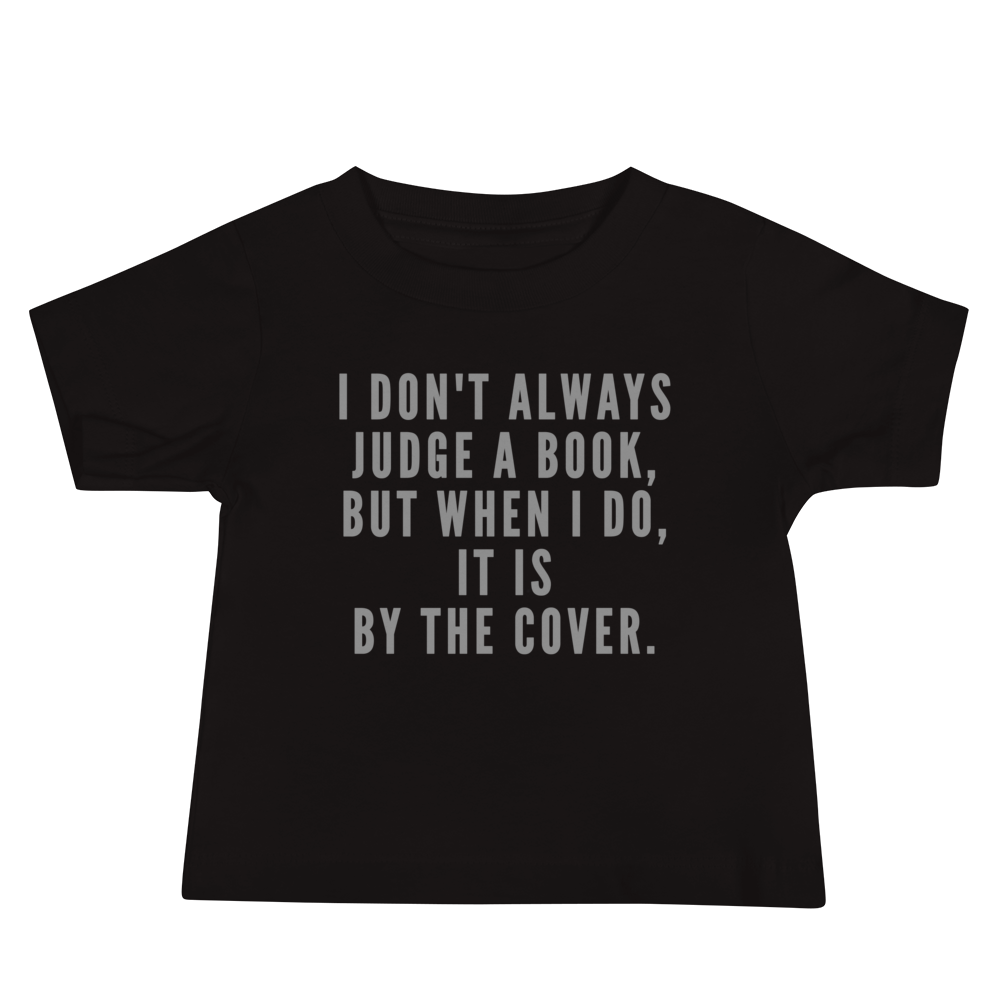 "I Don't always Judge a Book, but when I do, it's by the cover." printed on a black baby jersey short sleeve tee laying on a flat surface