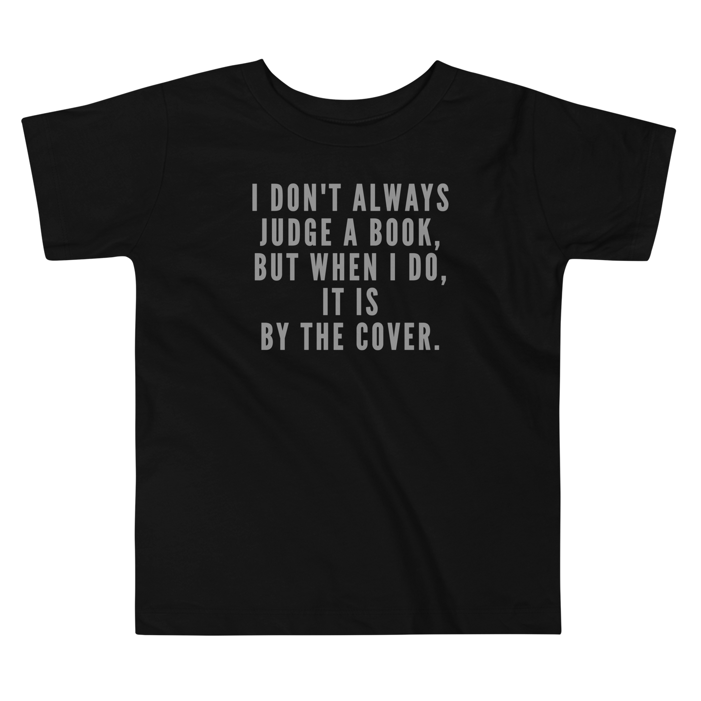 "I Don't always Judge a Book, but when I do, it's by the cover." printed on a black toddler short sleeve tee laying on a flat surface