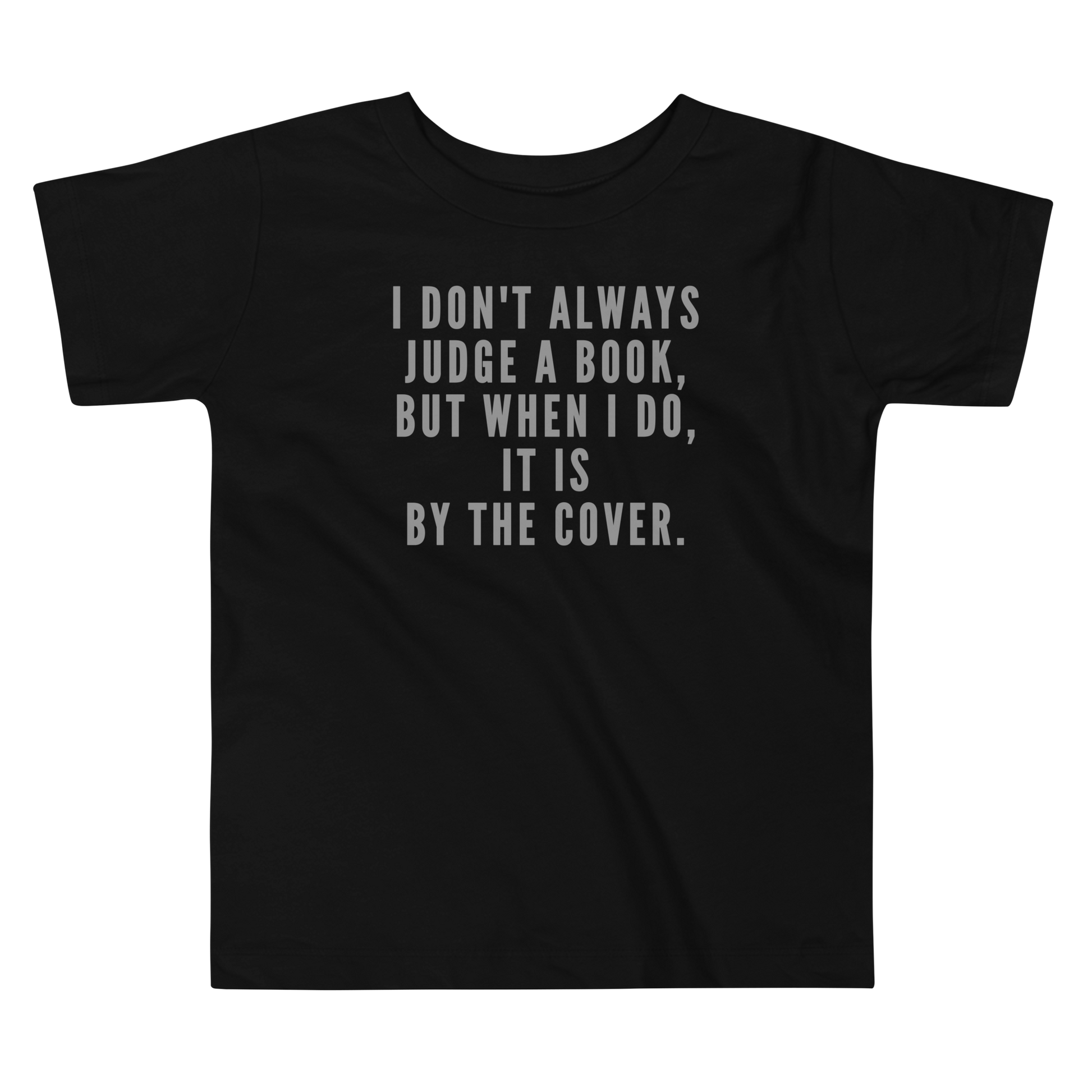 "I Don't always Judge a Book, but when I do, it's by the cover." printed on a black toddler short sleeve tee laying on a flat surface