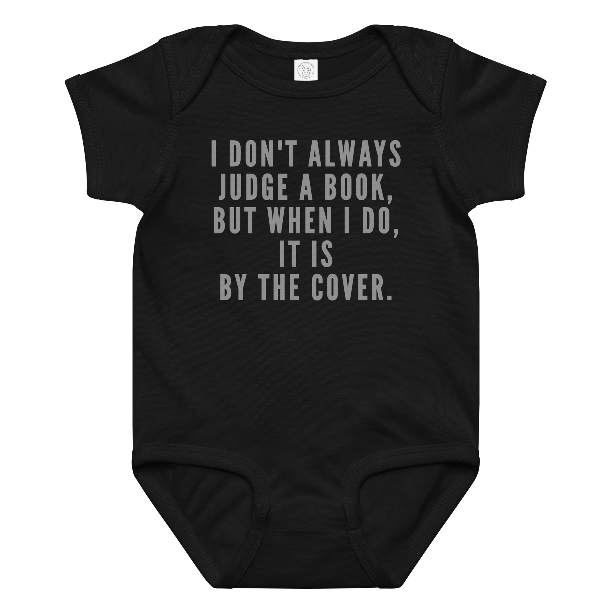 "I Don't always Judge a Book, but when I do, it's by the cover." printed on a black baby jersey bodysuit laying on a flat surface amongst other clothes
