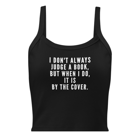 "I Don't always Judge a Book, but when I do, it's by the cover." printed on a solid black blend women's micro-rib tanktop laying on a flat surface