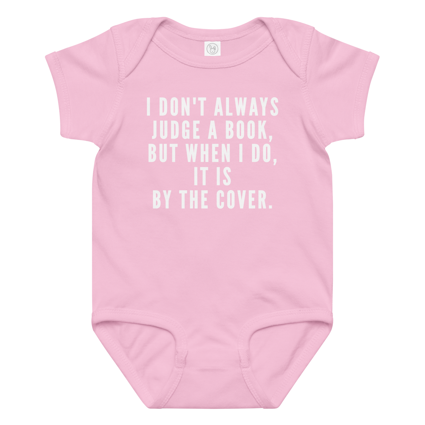 "I Don't always Judge a Book, but when I do, it's by the cover." printed on a pink baby jersey bodysuit laying on a flat surface amongst other clothes