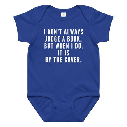 "I Don't always Judge a Book, but when I do, it's by the cover." printed on a royal baby jersey bodysuit laying on a flat surface amongst other clothes