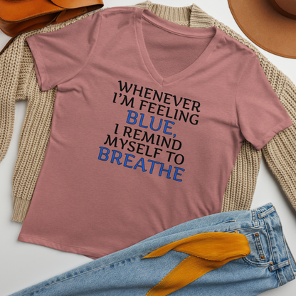 "Whenever I'm feeling blue, I remind myself to breathe" printed on a heather mauve women's relaxed v-neck t-shirt laying on a flat surface amongst other clothes