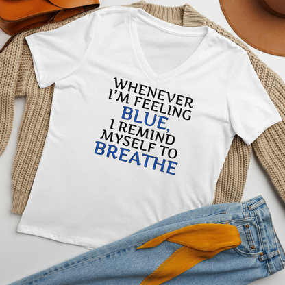 "Whenever I'm feeling blue, I remind myself to breathe" printed on a solid white blend women's relaxed v-neck t-shirt laying on a flat surface amongst other clothes