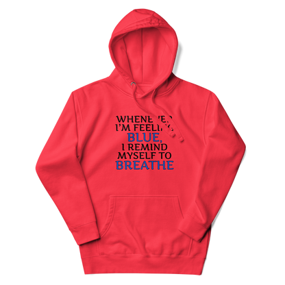 "Whenever I'm feeling blue, I remind myself to breathe" printed on a team red unisex hoodie laying on a flat surface with the hood up