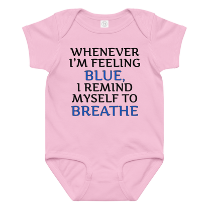 "Whenever I'm feeling blue, I remind myself to breathe" printed on a pink baby jersey bodysuit laying on a flat surface amongst other clothes