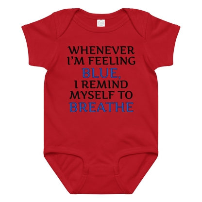 "Whenever I'm feeling blue, I remind myself to breathe" printed on a red baby jersey bodysuit laying on a flat surface amongst other clothes