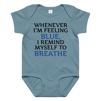 "Whenever I'm feeling blue, I remind myself to breathe" printed on a vintage indigo baby jersey bodysuit laying on a flat surface amongst other clothes