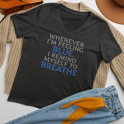 "Whenever I'm feeling blue, I remind myself to breathe" printed on a dark grey heather women's relaxed v-neck t-shirt laying on a flat surface amongst other clothes