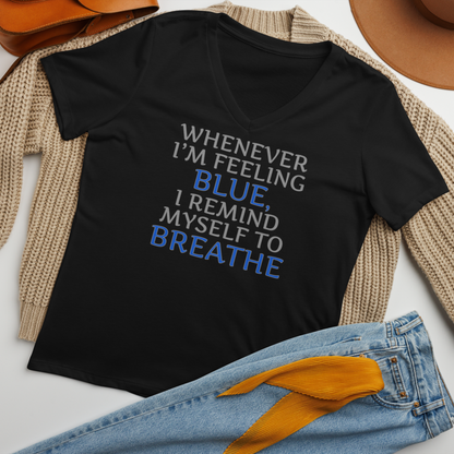 "Whenever I'm feeling blue, I remind myself to breathe" printed on a solid black blend women's relaxed v-neck t-shirt laying on a flat surface amongst other clothes