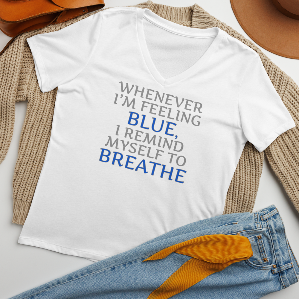 "Whenever I'm feeling blue, I remind myself to breathe" printed on a solid white blend women's relaxed v-neck t-shirt laying on a flat surface amongst other clothes