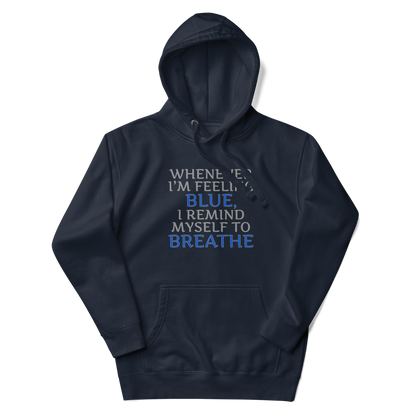 "Whenever I'm feeling blue, I remind myself to breathe" printed on a navy blazer unisex hoodie laying on a flat surface with the hood up
