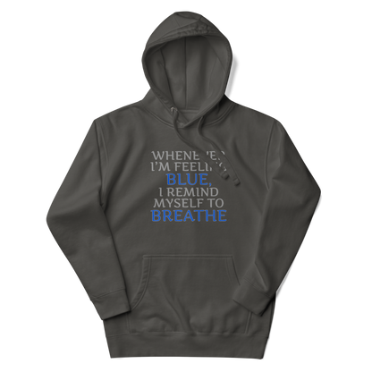 "Whenever I'm feeling blue, I remind myself to breathe" printed on a vintage black unisex hoodie laying on a flat surface with the hood up