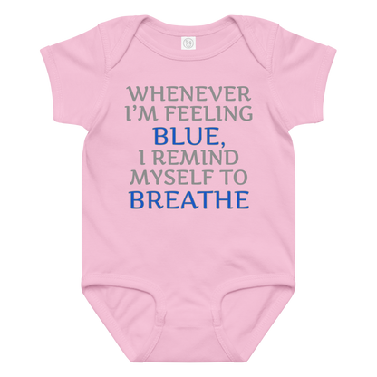 "Whenever I'm feeling blue, I remind myself to breathe" printed on a pink baby jersey bodysuit laying on a flat surface amongst other clothes