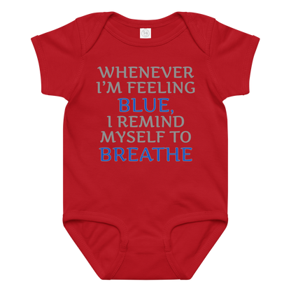 "Whenever I'm feeling blue, I remind myself to breathe" printed on a red baby jersey bodysuit laying on a flat surface amongst other clothes