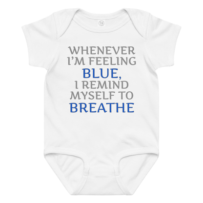 "Whenever I'm feeling blue, I remind myself to breathe" printed on a white baby jersey bodysuit laying on a flat surface amongst other clothes