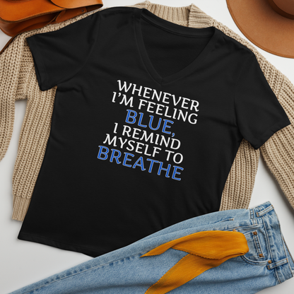 "Whenever I'm feeling blue, I remind myself to breathe" printed on a solid black blend women's relaxed v-neck t-shirt laying on a flat surface amongst other clothes