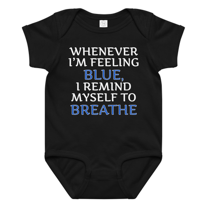 "Whenever I'm feeling blue, I remind myself to breathe" printed on a black baby jersey bodysuit laying on a flat surface amongst other clothes