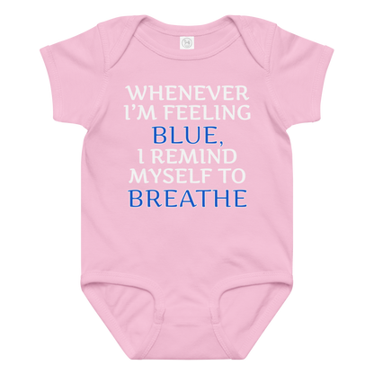 "Whenever I'm feeling blue, I remind myself to breathe" printed on a pink baby jersey bodysuit laying on a flat surface amongst other clothes
