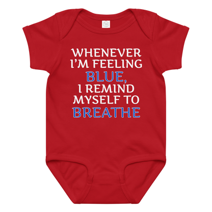 "Whenever I'm feeling blue, I remind myself to breathe" printed on a red baby jersey bodysuit laying on a flat surface amongst other clothes