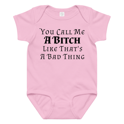 "You Call Me A Bitch Like That's A Bad Thing" printed on a pink baby jersey bodysuit laying on a flat surface amongst other clothes