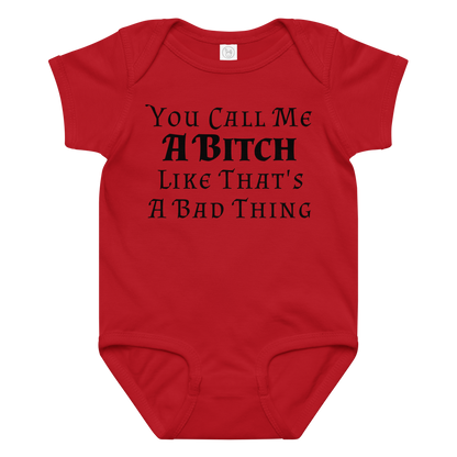 "You Call Me A Bitch Like That's A Bad Thing" printed on a red baby jersey bodysuit laying on a flat surface amongst other clothes