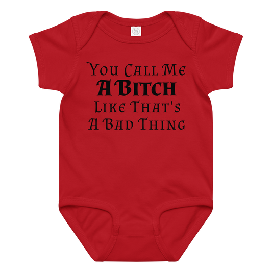 "You Call Me A Bitch Like That's A Bad Thing" printed on a red baby jersey bodysuit laying on a flat surface amongst other clothes