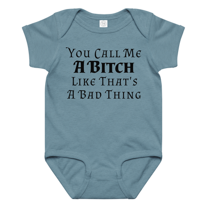 "You Call Me A Bitch Like That's A Bad Thing" printed on a vintage indigo baby jersey bodysuit laying on a flat surface amongst other clothes